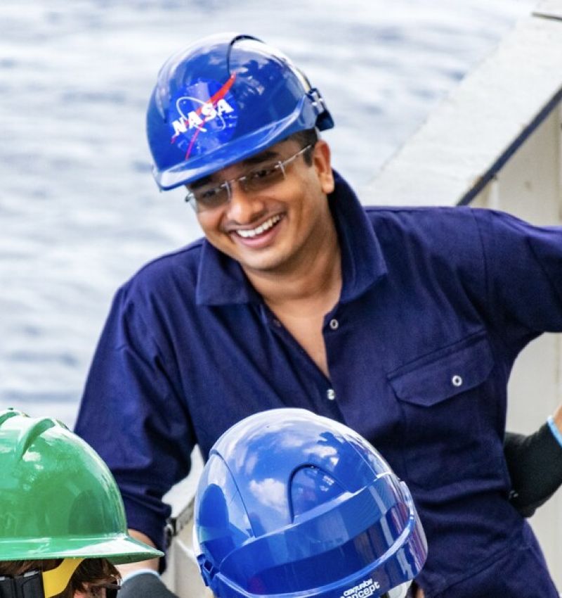 Smilender arbeider med blå hjelm